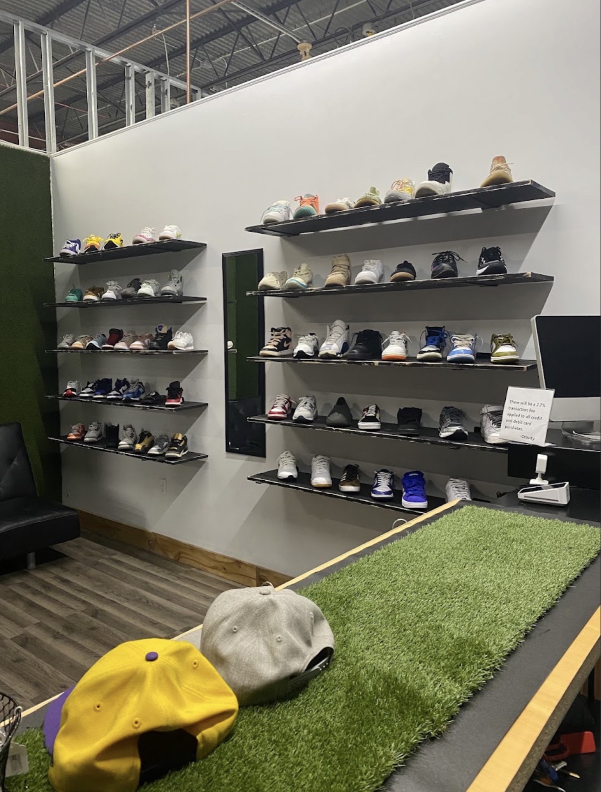 Wall of sneakers on black floating shelves at Gravity Sneakers